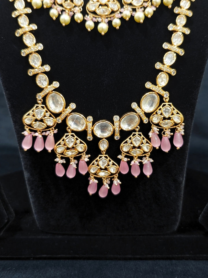 Close-up of an ornate traditional (Gold Polish) Long jewellery set and earrings with Polki, American Diamond, Tumble Beads and Pearls. Festive celebration look completed with premium imitation Polki jewelry. Woman wearing trending Polki artificial jewelry for the wedding season in India.