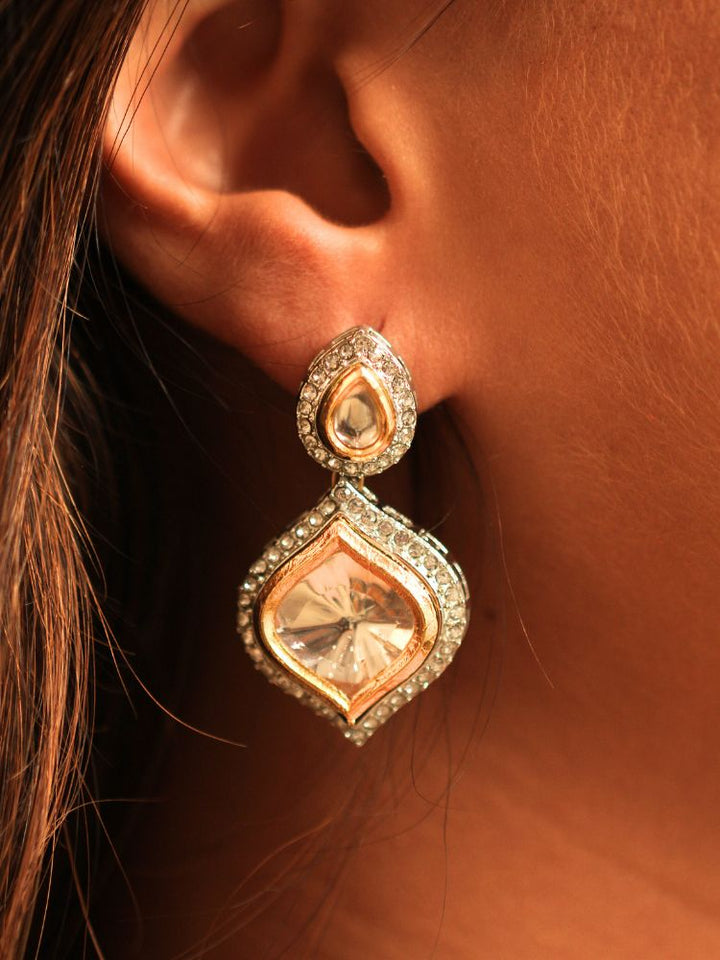 A woman with long dark hair wears the Moissanite Susan Necklace Set—gold and silver Kundan necklace surrounded by American Diamonds, with matching earrings—gazing neutrally at the camera, effortlessly highlighting this luxury jewelry.