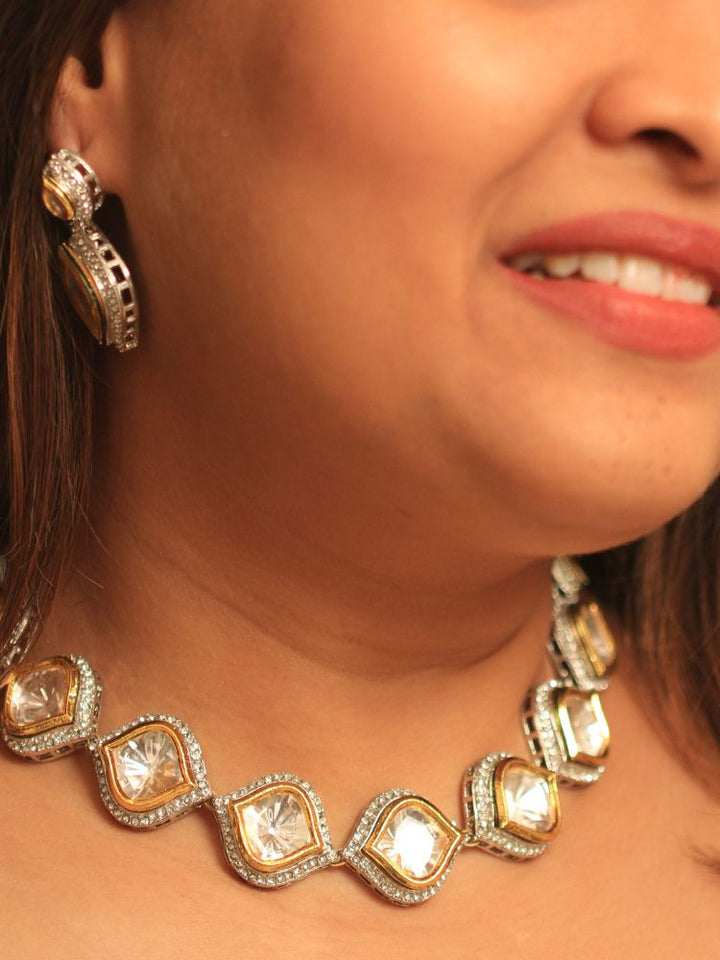 A woman with long dark hair wears the Moissanite Susan Necklace Set—gold and silver Kundan necklace surrounded by American Diamonds, with matching earrings—gazing neutrally at the camera, effortlessly highlighting this luxury jewelry.