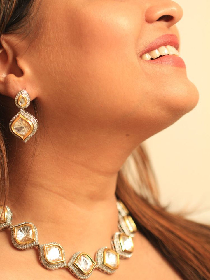 A woman with long dark hair wears the Moissanite Susan Necklace Set—gold and silver Kundan necklace surrounded by American Diamonds, with matching earrings—gazing neutrally at the camera, effortlessly highlighting this luxury jewelry.