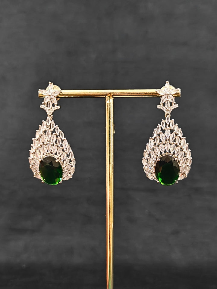 Close-up of an ornate Western Green Diamond Silver Collar jewellery set and earrings with American Diamond and Green Colored Stones. A luxury American diamond necklace set styled beautifully for a wedding guest look in India. Elegant wedding jewelry look featuring a premium artificial American diamond necklace.