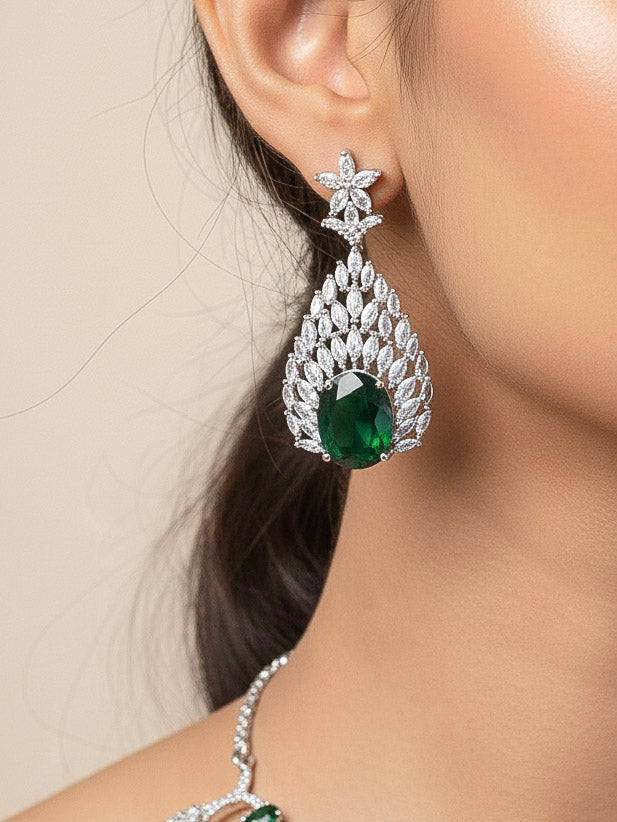 Close-up of a woman wearing an ornate Western Green Diamond Silver Collar jewellery set and earrings with American Diamond and Green Colored Stones. A woman wearing a luxury American diamond necklace set styled beautifully for a wedding guest look in India. Elegant wedding jewelry look featuring a premium artificial American diamond necklace.