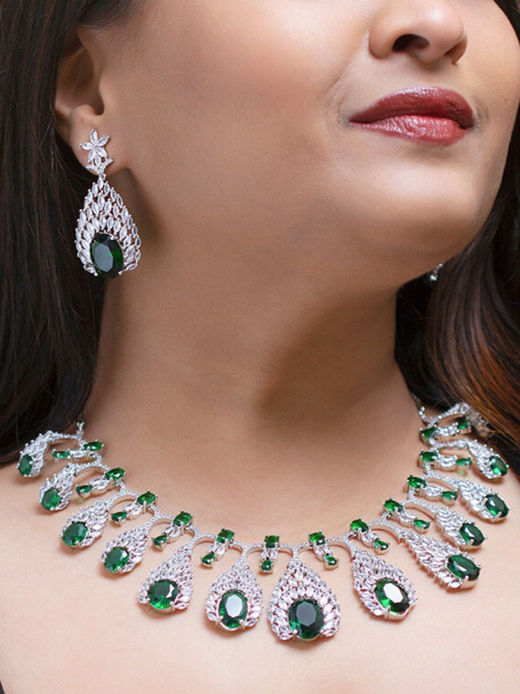 Close-up of a woman wearing an ornate Western Green Diamond Silver Collar jewellery set and earrings with American Diamond and Green Colored Stones. A woman wearing a luxury American diamond necklace set styled beautifully for a wedding guest look in India. Elegant wedding jewelry look featuring a premium artificial American diamond necklace.