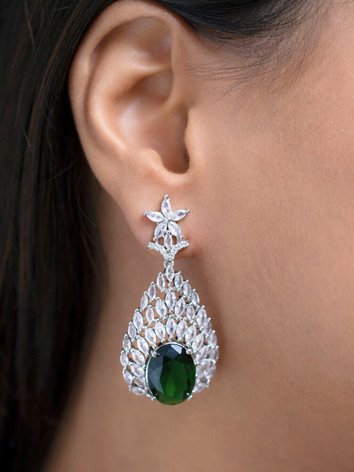 Close-up of a woman wearing an ornate Western Green Diamond Silver Collar jewellery set and earrings with American Diamond and Green Colored Stones. A woman wearing a luxury American diamond necklace set styled beautifully for a wedding guest look in India. Elegant wedding jewelry look featuring a premium artificial American diamond necklace.