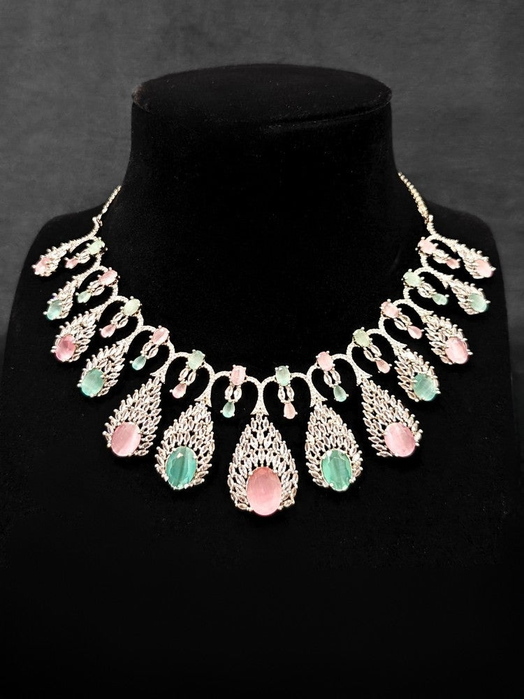 Close-up of an ornate Western Pink & Green Diamond Silver Collar jewellery set and earrings with American Diamond and Colored Stones. A luxury American diamond necklace set styled beautifully for a wedding guest look in India. Elegant wedding jewelry look featuring a premium artificial American diamond necklace.
