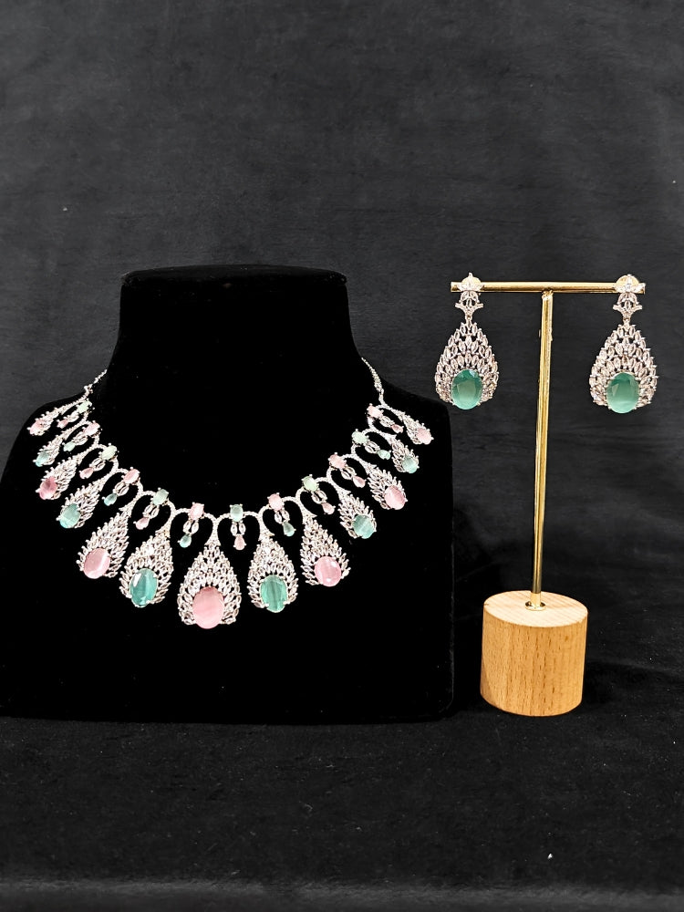 Close-up of an ornate Western Pink & Green Diamond Silver Collar jewellery set and earrings with American Diamond and Colored Stones. A luxury American diamond necklace set styled beautifully for a wedding guest look in India. Elegant wedding jewelry look featuring a premium artificial American diamond necklace.