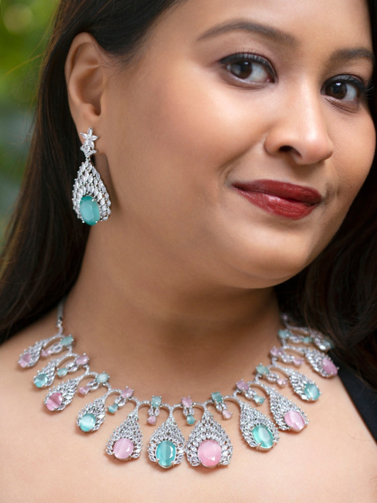Close-up of a woman wearing an ornate Western Pink & Green Diamond Silver Collar jewellery set and earrings with American Diamond and Colored Stones. A woman wearing a luxury American diamond necklace set styled beautifully for a wedding guest look in India. Elegant wedding jewelry look featuring a premium artificial American diamond necklace.