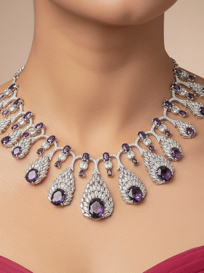 Close-up of a woman wearing an ornate Western Purple Diamond Silver Collar jewellery set and earrings with American Diamond and Purple Colored Stones. A woman wearing a luxury American diamond necklace set styled beautifully for a wedding guest look in India. Elegant wedding jewelry look featuring a premium artificial American diamond necklace.