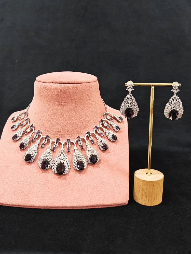 Close-up of an ornate Western Purple Diamond Silver Collar jewellery set and earrings with American Diamond and Purple Colored Stones. A luxury American diamond necklace set styled beautifully for a wedding guest look in India. Elegant wedding jewelry look featuring a premium artificial American diamond necklace.