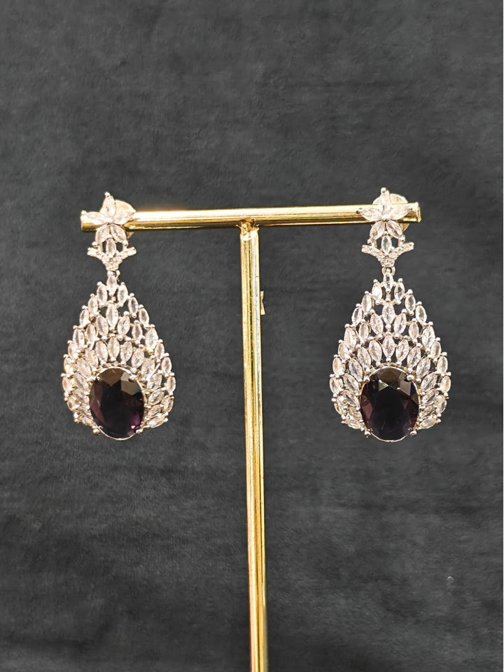 Close-up of an ornate Western Purple Diamond Silver Collar jewellery set and earrings with American Diamond and Purple Colored Stones. A luxury American diamond necklace set styled beautifully for a wedding guest look in India. Elegant wedding jewelry look featuring a premium artificial American diamond necklace.