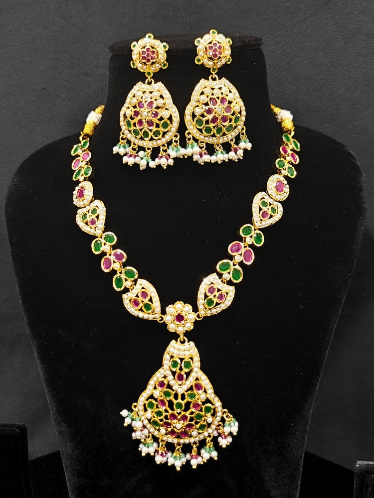 Close-up of an ornate traditional Collar jadau gold jewellery set and jadau earrings with Pearl and Pink and Green gemstones. Festive saree look completed with a handcrafted Jadau necklace.
Festive celebration look featuring a Jadau artificial necklace.