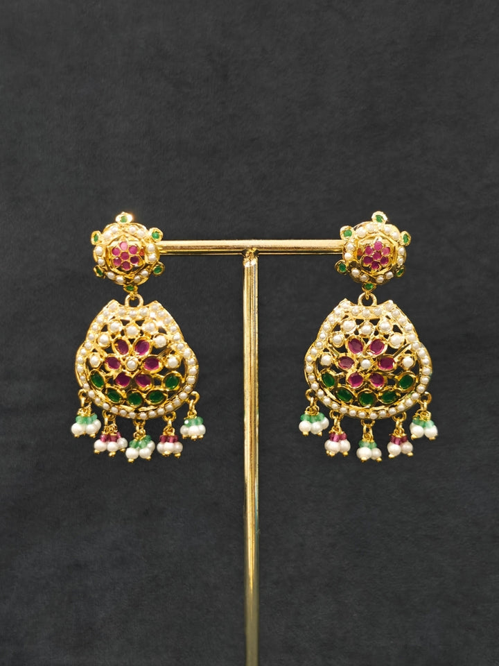 Close-up of an ornate traditional Collar jadau gold jewellery set and jadau earrings with Pearl and Pink and Green gemstones. Festive saree look completed with a handcrafted Jadau necklace.
Festive celebration look featuring a Jadau artificial necklace.