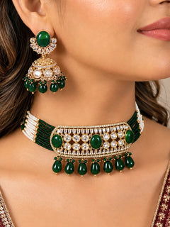 Close-up of a woman wearing an ornate traditional (Gold Polish) Choker Dark Green jewellery set and earrings with Crystal Beads, Polki, American Diamond, Colored Stones and Pearls. Festive Diwali look enhanced with a premium Polki artificial necklace. Festive saree look completed with Polki artificial jewelry set.