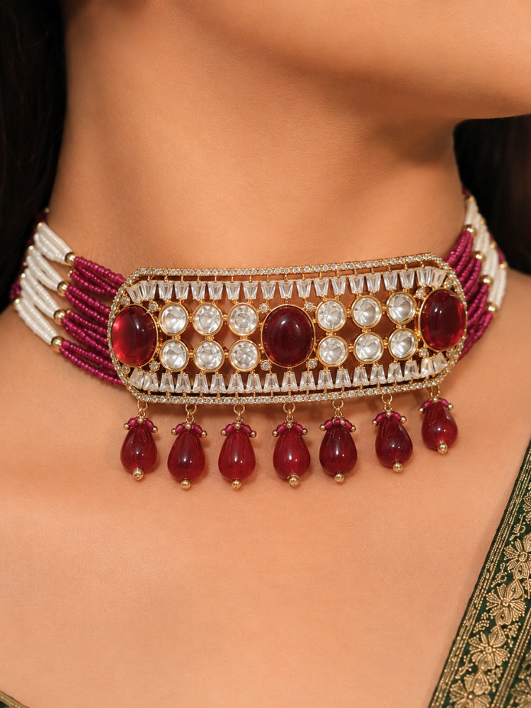 Close-up of a woman wearing an ornate traditional (Gold Polish) Choker Ruby Pink jewellery set and earrings with Crystal Beads, Polki, American Diamond, Colored Stones and Pearls. Festive Diwali look enhanced with a premium Polki artificial necklace. Festive saree look completed with Polki artificial jewelry set.