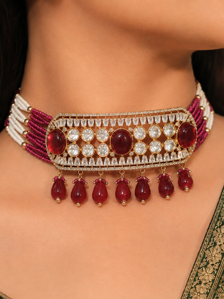 Close-up of a woman wearing an ornate traditional (Gold Polish) Choker Ruby Pink jewellery set and earrings with Crystal Beads, Polki, American Diamond, Colored Stones and Pearls. Festive Diwali look enhanced with a premium Polki artificial necklace. Festive saree look completed with Polki artificial jewelry set.