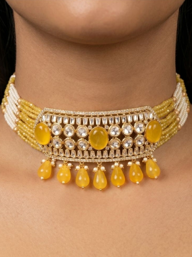 Close-up of a woman wearing an ornate traditional (Gold Polish) Choker Yellow jewellery set and earrings with Crystal Beads, Polki, American Diamond, Colored Stones and Pearls. Festive Diwali look enhanced with a premium Polki artificial necklace. Festive saree look completed with Polki artificial jewelry set.