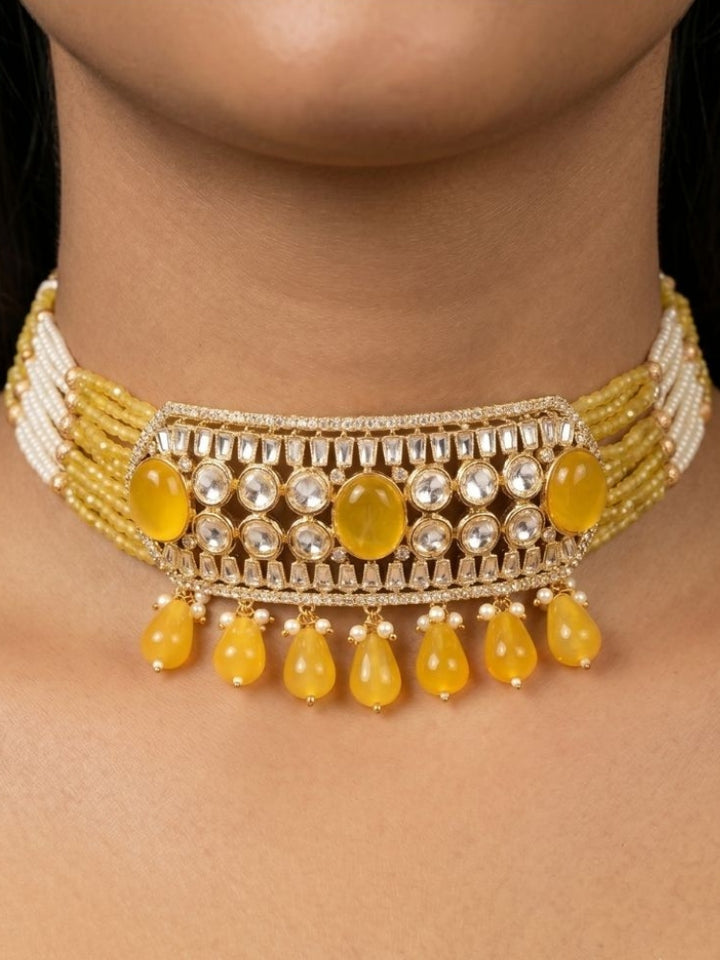 Close-up of a woman wearing an ornate traditional (Gold Polish) Choker Yellow jewellery set and earrings with Crystal Beads, Polki, American Diamond, Colored Stones and Pearls. Festive Diwali look enhanced with a premium Polki artificial necklace. Festive saree look completed with Polki artificial jewelry set.