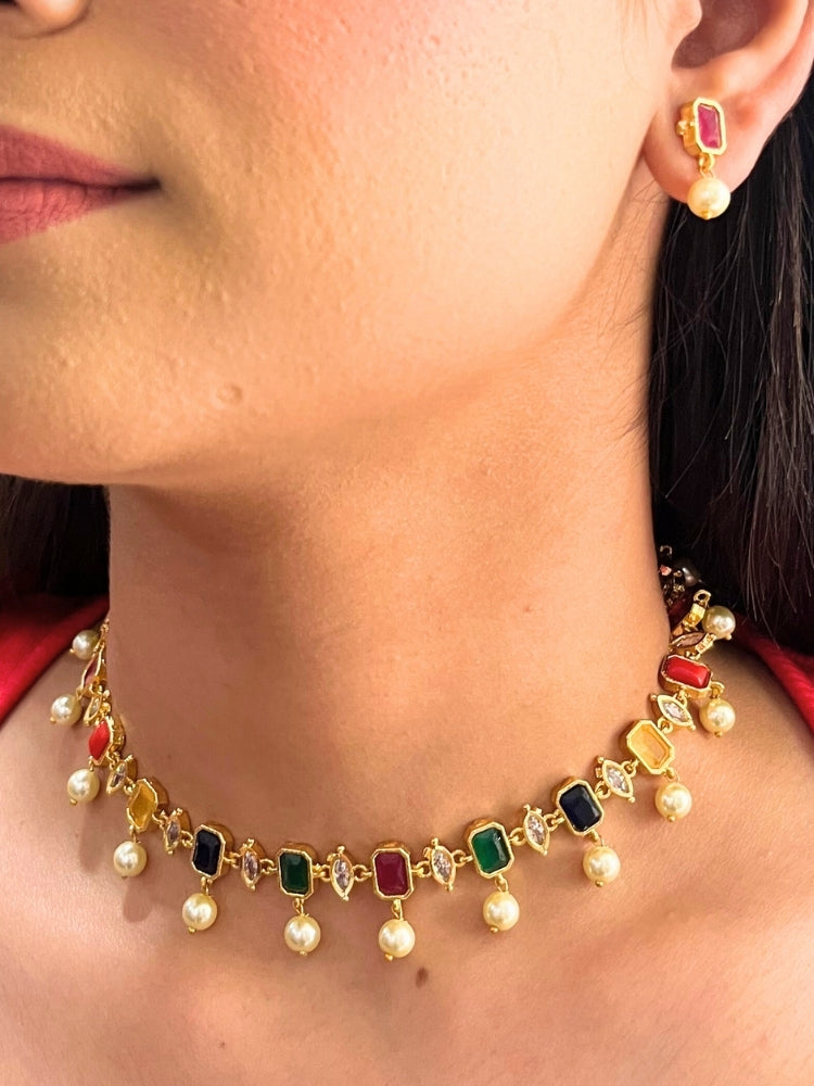 Close-up of a woman wearing the 
Multi Color Amelia Choker Necklace adorned with colored gemstones and dangling pearls, matching earrings, and a Multi Color top—an elegant choice for wedding ceremonies. Her lips are lightly colored, with dark hair partially visible.