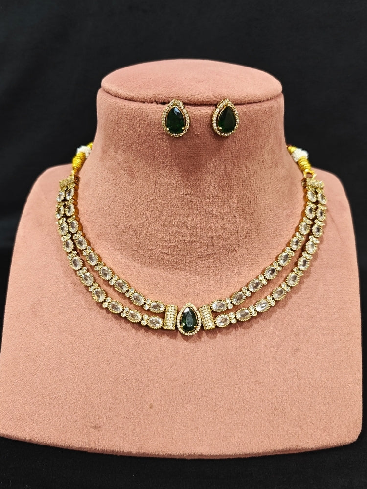 Close-up of an ornate Indo-western Green Collar Layered Diamond jewellery set and earrings with American Diamond and Colored Stones. Festive Diwali outfit styled with an American diamond artificial necklace. Party wear outfit completed with a lightweight American diamond necklace.