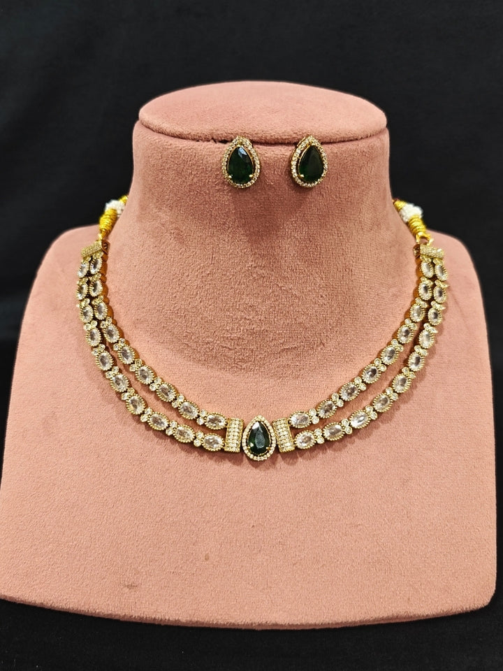Close-up of an ornate Indo-western Green Collar Layered Diamond jewellery set and earrings with American Diamond and Colored Stones. Festive Diwali outfit styled with an American diamond artificial necklace. Party wear outfit completed with a lightweight American diamond necklace.