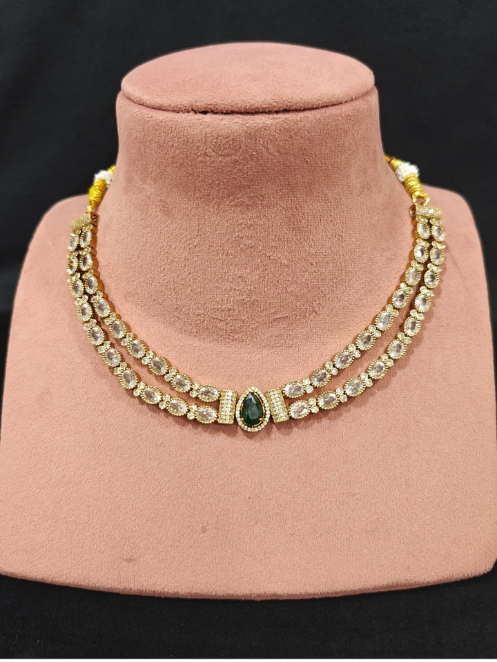 Close-up of an ornate Indo-western Green Collar Layered Diamond jewellery set and earrings with American Diamond and Colored Stones. Festive Diwali outfit styled with an American diamond artificial necklace. Party wear outfit completed with a lightweight American diamond necklace.