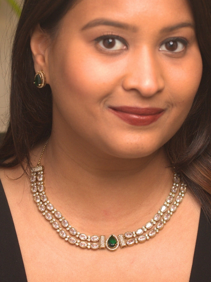 Close-up of a woman wearing an ornate Indo-western Green Collar Layered Diamond jewellery set and earrings with American Diamond and Colored Stones. Festive Diwali outfit styled with an American diamond artificial necklace. Party wear outfit completed with a lightweight American diamond necklace.