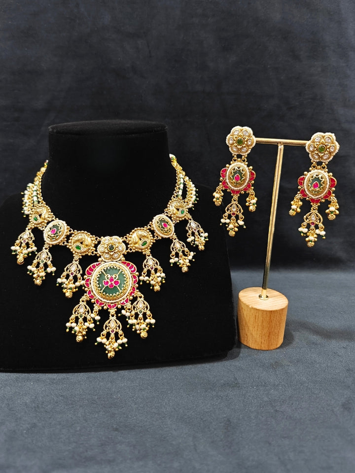 Close-up of an ornate traditional Heritage gold Collar jewellery set and earrings with Pearls and Colored Stone. Close-up of antique-style detailing in heritage artificial jewelry. Festive outfit styled with a royal heritage necklace.