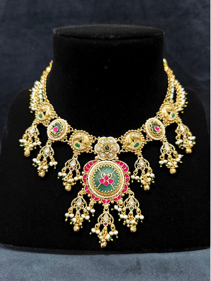Close-up of an ornate traditional Heritage gold Collar jewellery set and earrings with Pearls and Colored Stone. Close-up of antique-style detailing in heritage artificial jewelry. Festive outfit styled with a royal heritage necklace.