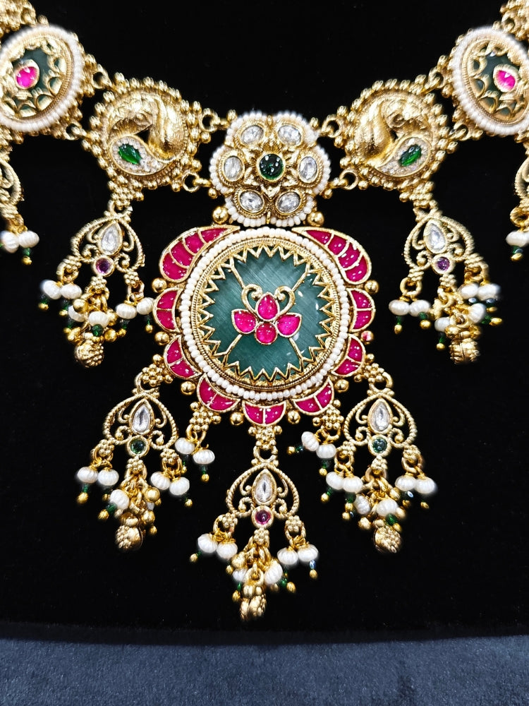Close-up of an ornate traditional Heritage gold Collar jewellery set and earrings with Pearls and Colored Stone. Close-up of antique-style detailing in heritage artificial jewelry. Festive outfit styled with a royal heritage necklace.