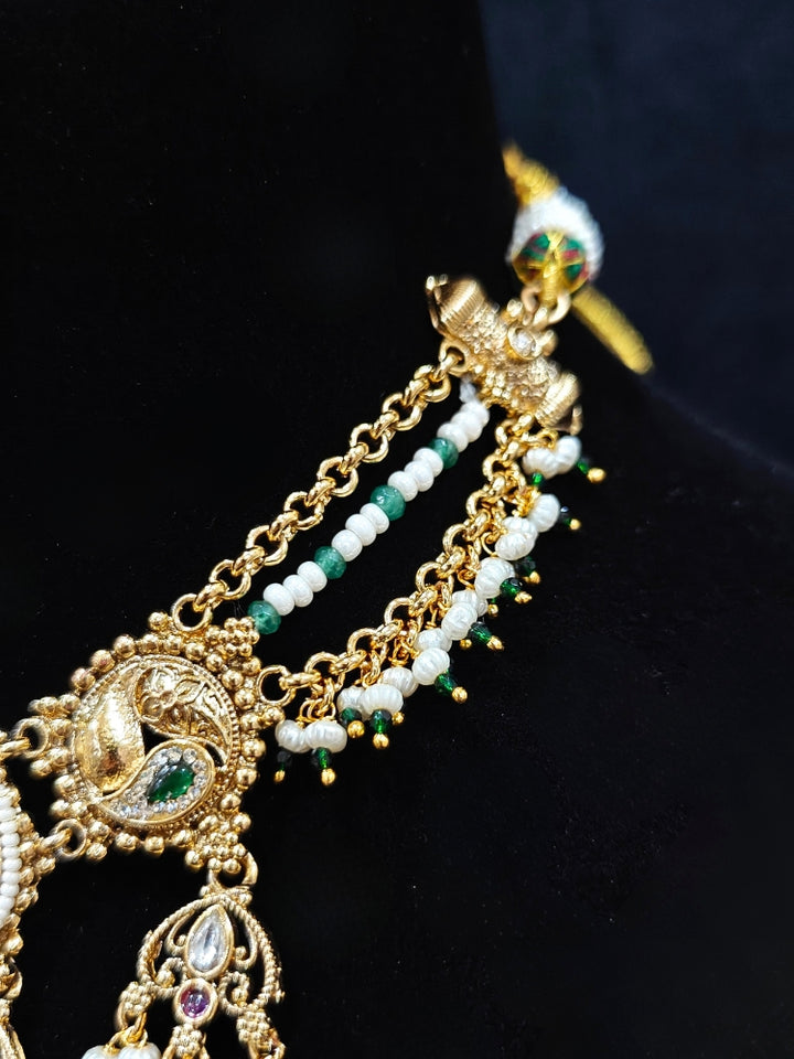 Close-up of an ornate traditional Heritage gold Collar jewellery set and earrings with Pearls and Colored Stone. Close-up of antique-style detailing in heritage artificial jewelry. Festive outfit styled with a royal heritage necklace.