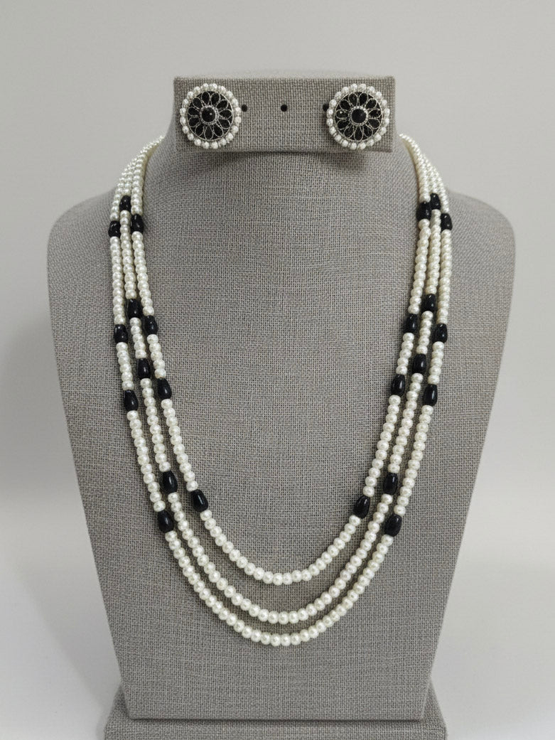 Close-up of an ornate Indo-Western White and Black Layered Jewellery Set and Earrings with Pearls and BLack Colored Beads. Indo-western outfit styled with an artifical Pearl Necklace Set. 
