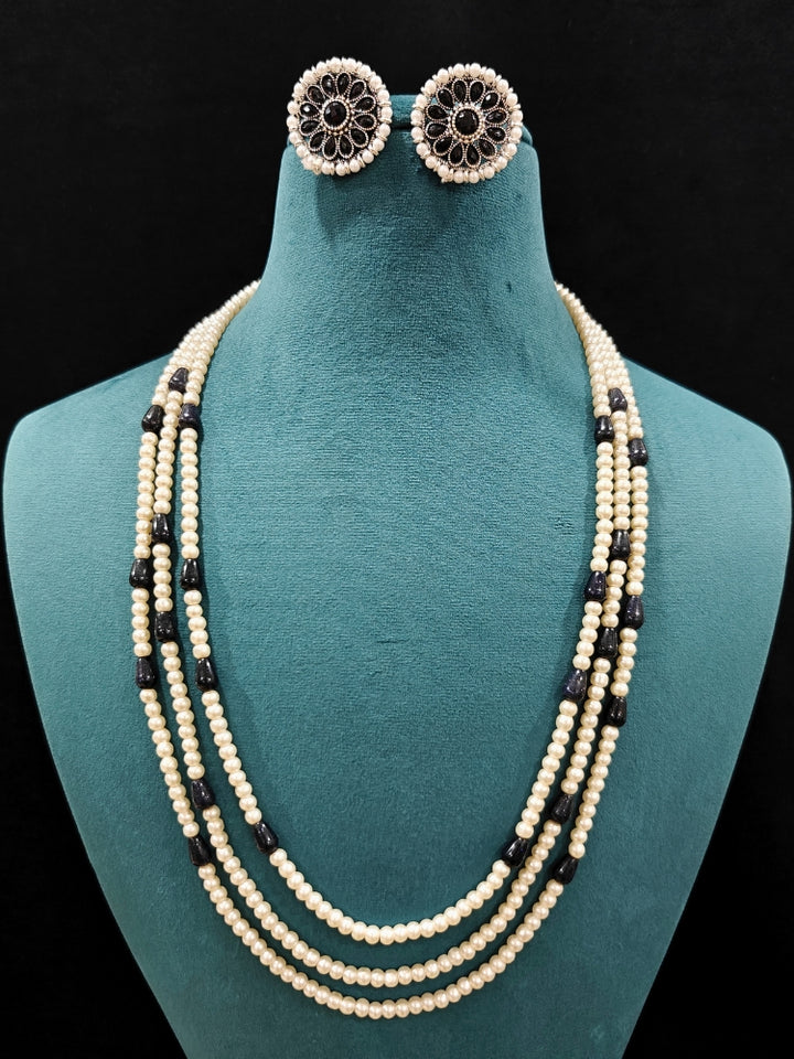 Close-up of an ornate Indo-Western White and Black Layered Jewellery Set and Earrings with Pearls and BLack Colored Beads. Indo-western outfit styled with an artifical Pearl Necklace Set. 