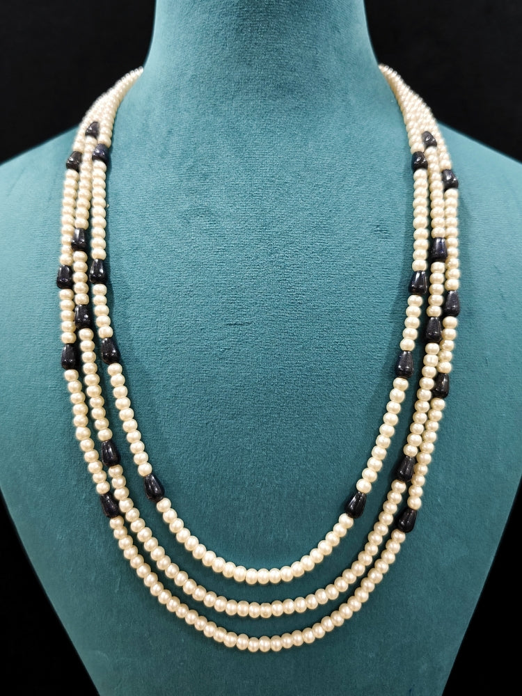 Close-up of an ornate Indo-Western White and Black Layered Jewellery Set and Earrings with Pearls and BLack Colored Beads. Indo-western outfit styled with an artifical Pearl Necklace Set. 
