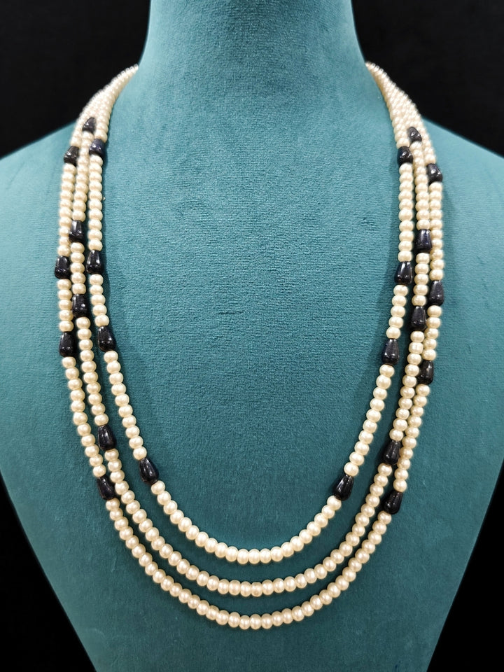 Close-up of an ornate Indo-Western White and Black Layered Jewellery Set and Earrings with Pearls and BLack Colored Beads. Indo-western outfit styled with an artifical Pearl Necklace Set. 