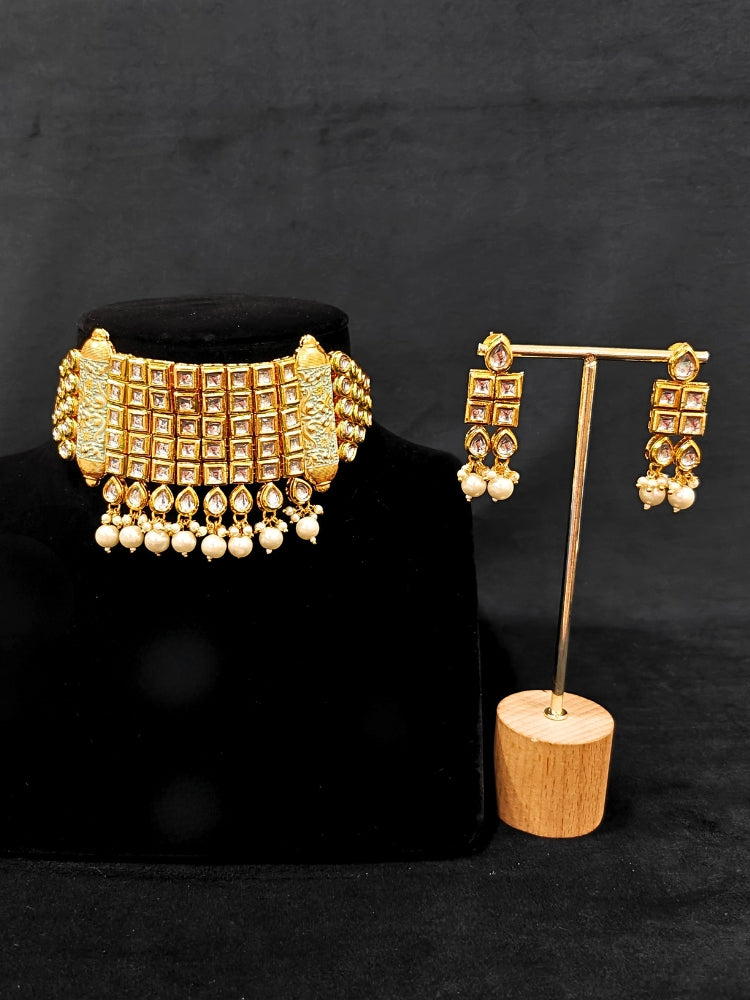 Close-up of an ornate traditional Meenakari gold Choker jewellery set and earrings with Kundan, Meenakari and Pearls. Reception party styling featuring a premium Meenakari imitation set. Close-up of detailed enamel craftsmanship in Meenakari jewelry.