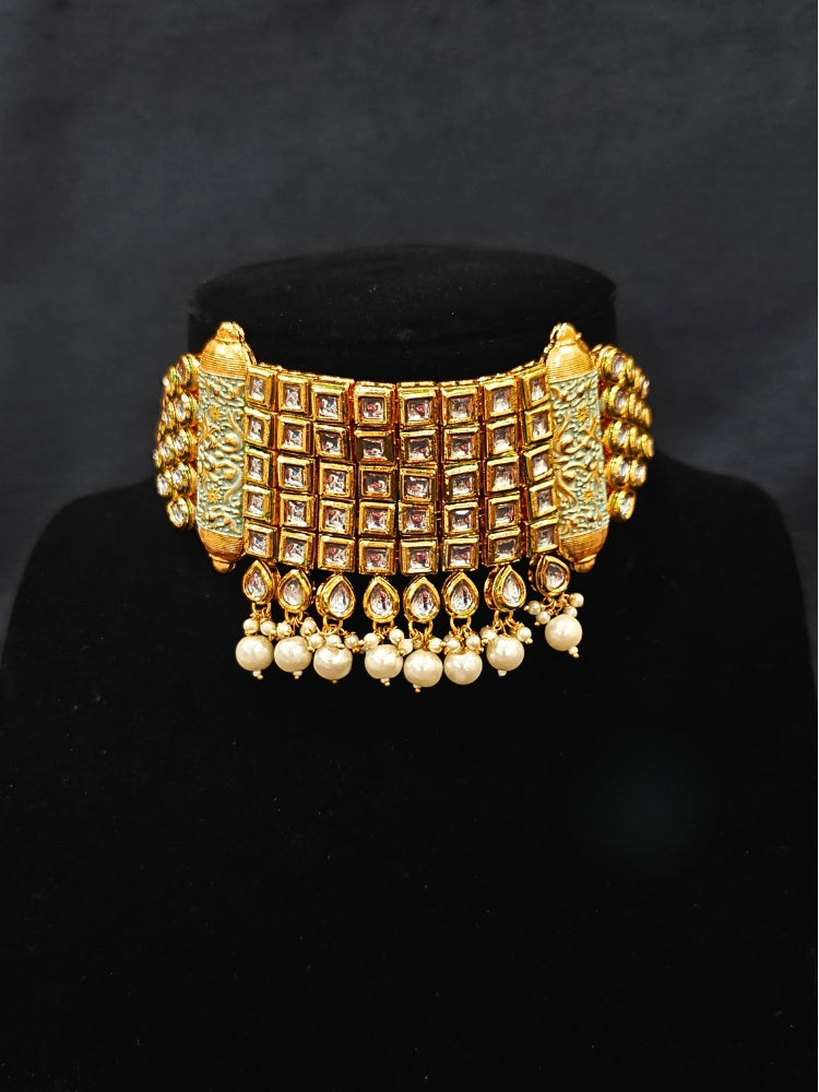 Close-up of an ornate traditional Meenakari gold Choker jewellery set and earrings with Kundan, Meenakari and Pearls. Reception party styling featuring a premium Meenakari imitation set. Close-up of detailed enamel craftsmanship in Meenakari jewelry.