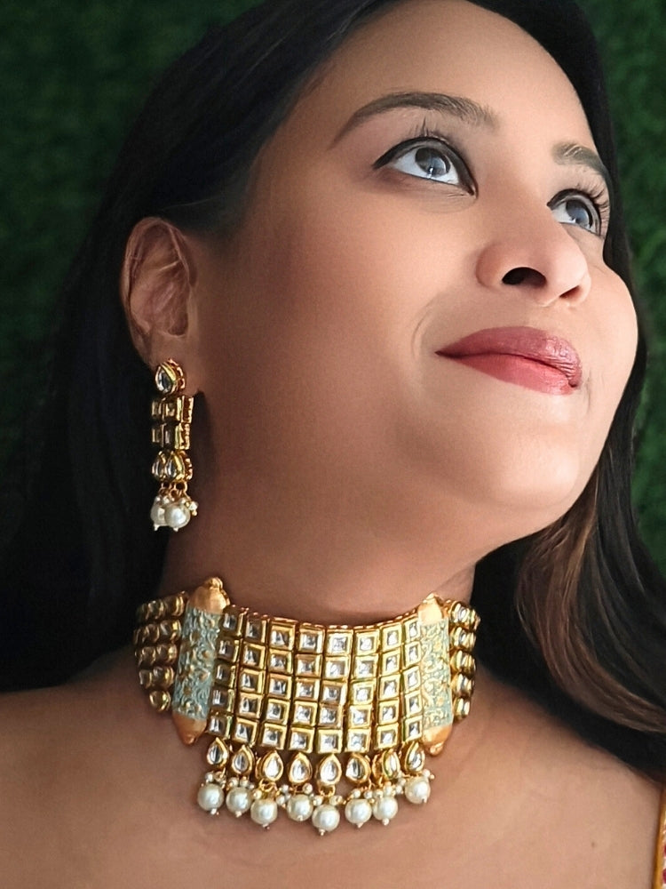 Close-up of a woman wearing an ornate traditional Meenakari gold Choker jewellery set and earrings with Kundan, Meenakari and Pearls. Reception party styling featuring a premium Meenakari imitation set. Close-up of detailed enamel craftsmanship in Meenakari jewelry.