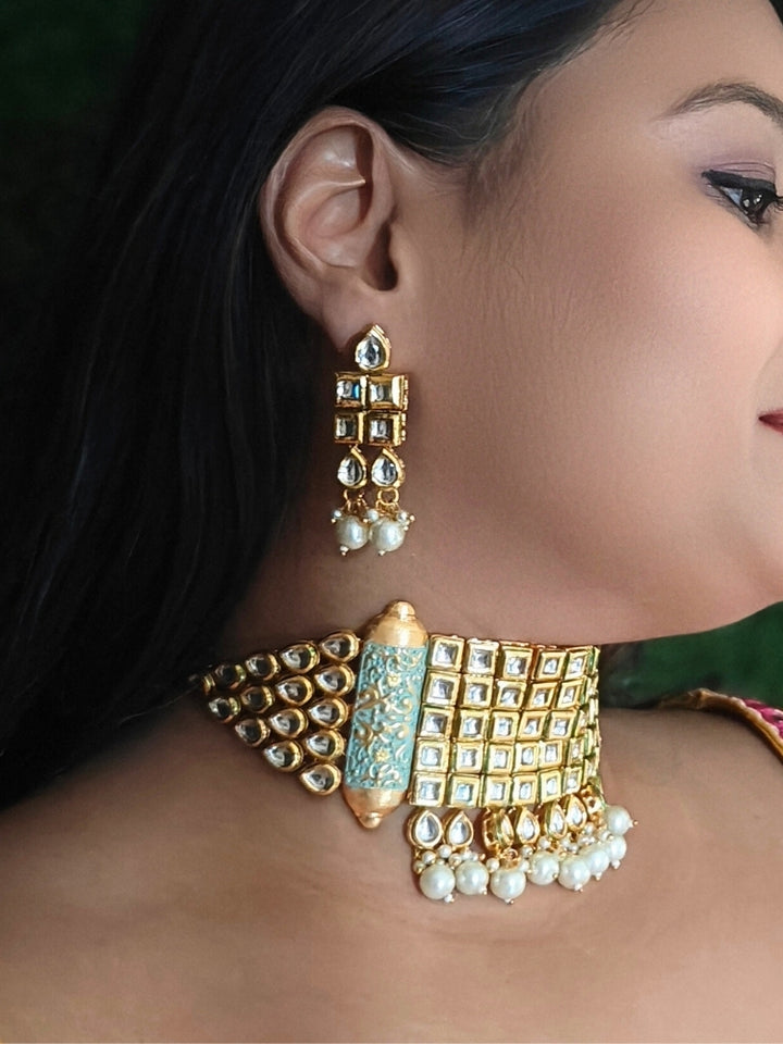 Close-up of a woman wearing an ornate traditional Meenakari gold Choker jewellery set and earrings with Kundan, Meenakari and Pearls. Reception party styling featuring a premium Meenakari imitation set. Close-up of detailed enamel craftsmanship in Meenakari jewelry.