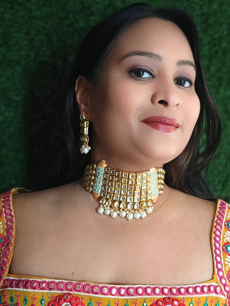 Close-up of a woman wearing an ornate traditional Meenakari gold Choker jewellery set and earrings with Kundan, Meenakari and Pearls. Reception party styling featuring a premium Meenakari imitation set. Close-up of detailed enamel craftsmanship in Meenakari jewelry.