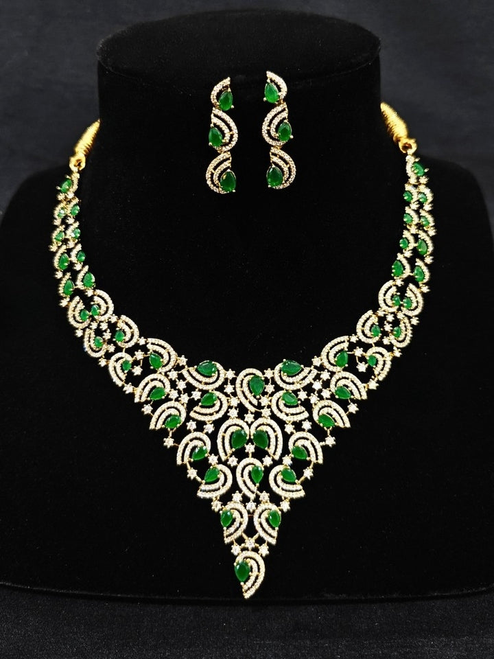 Close-up of a woman wearing an ornate Indo-Western Green Diamond gold Collar jewellery set and earrings with American Diamond and Green Colored Stones. Close-up of a cocktail party look featuring a premium American diamond necklace. Mehendi function outfit styled with a lightweight American Diamond necklace.