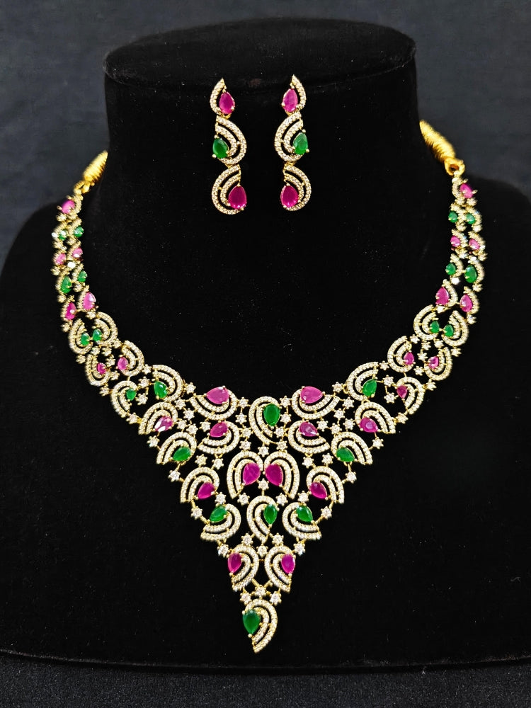Close-up of an ornate Indo-Western Ruby Pink & Green Diamond gold Collar jewellery set and earrings with American Diamond and Ruby Pink & Green Colored Stones. Close-up of a cocktail party look featuring a premium American diamond necklace. Mehendi function outfit styled with a lightweight American Diamond necklace.