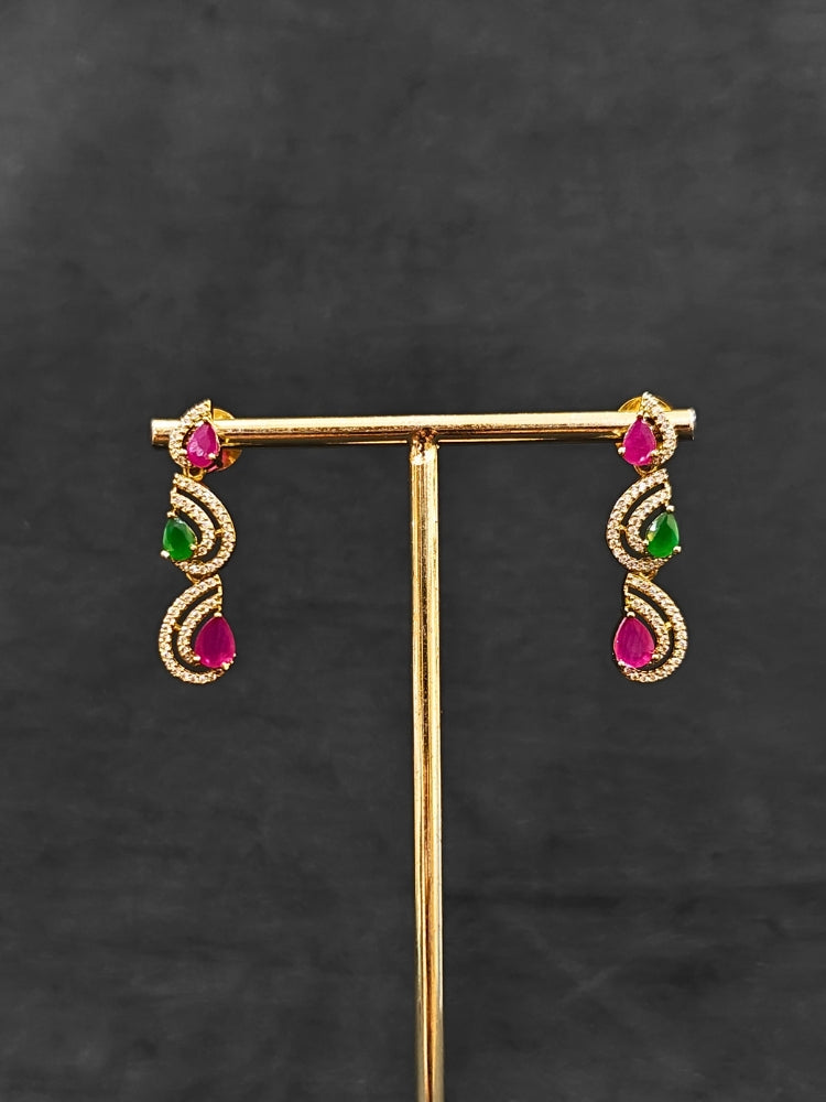 Close-up of an ornate Indo-Western Ruby Pink & Green Diamond gold Collar jewellery set and earrings with American Diamond and Ruby Pink & Green Colored Stones. Close-up of a cocktail party look featuring a premium American diamond necklace. Mehendi function outfit styled with a lightweight American Diamond necklace.