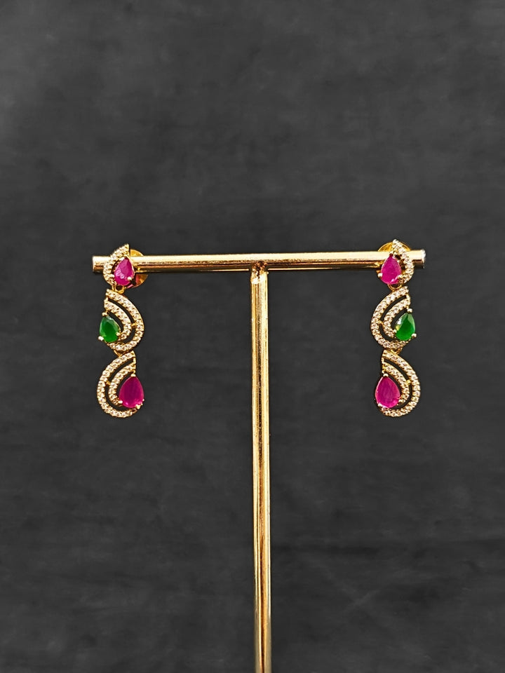Close-up of an ornate Indo-Western Ruby Pink & Green Diamond gold Collar jewellery set and earrings with American Diamond and Ruby Pink & Green Colored Stones. Close-up of a cocktail party look featuring a premium American diamond necklace. Mehendi function outfit styled with a lightweight American Diamond necklace.