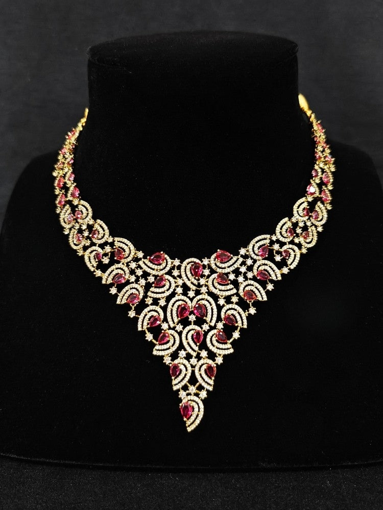 Close-up of an ornate Indo-Western Red Diamond gold Collar jewellery set and earrings with American Diamond and Red Colored Stones. Close-up of a cocktail party look featuring a premium American diamond necklace. Mehendi function outfit styled with a lightweight American Diamond necklace.