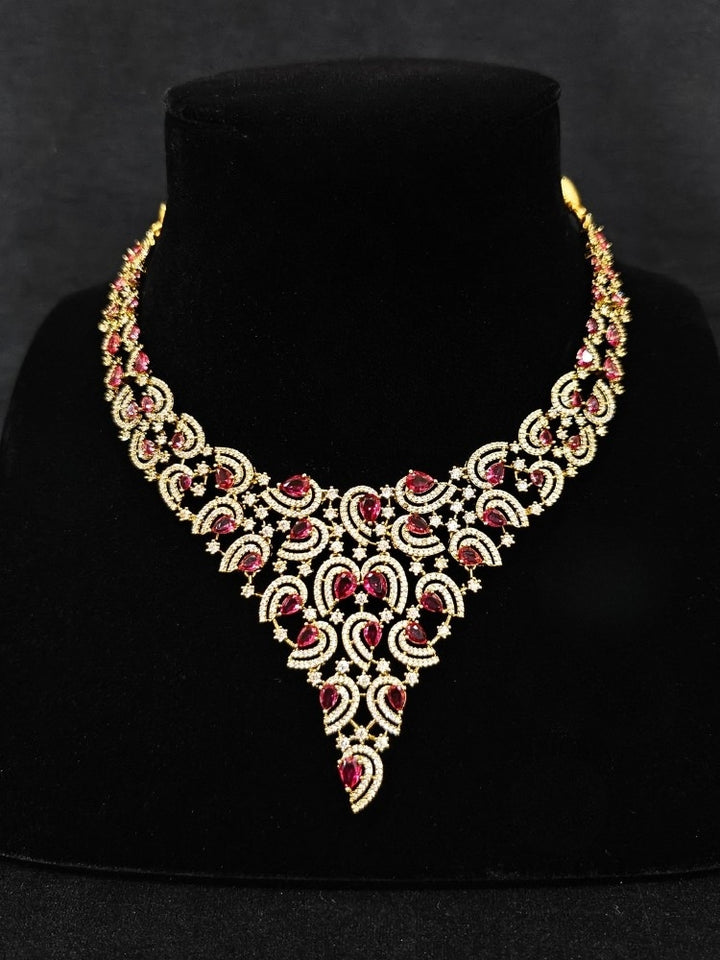 Close-up of an ornate Indo-Western Red Diamond gold Collar jewellery set and earrings with American Diamond and Red Colored Stones. Close-up of a cocktail party look featuring a premium American diamond necklace. Mehendi function outfit styled with a lightweight American Diamond necklace.