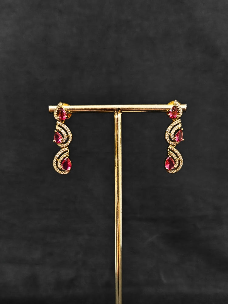 Close-up of an ornate Indo-Western Red Diamond gold Collar jewellery set and earrings with American Diamond and Red Colored Stones. Close-up of a cocktail party look featuring a premium American diamond necklace. Mehendi function outfit styled with a lightweight American Diamond necklace.