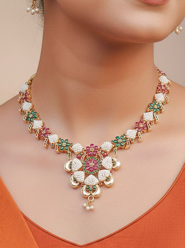 Close-up of a woman wearing an ornate traditional (Bright Gold Polish) Red,Green and White Collar jewellery set and earrings and Ring with Pearls and Red & Green Colored Stones. Mehendi ceremony look completed with a handcrafted Pearl jewelry set. Woman wearing a vibrant Pearl artificial jewelry set for celebrations.