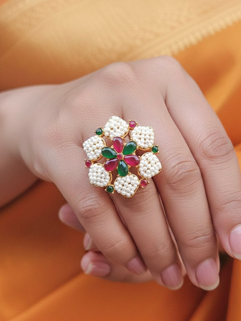 Close-up of a woman wearing an ornate traditional (Bright Gold Polish) Red,Green and White Collar jewellery set and earrings and Ring with Pearls and Red & Green Colored Stones. Mehendi ceremony look completed with a handcrafted Pearl jewelry set. Woman wearing a vibrant Pearl artificial jewelry set for celebrations.
