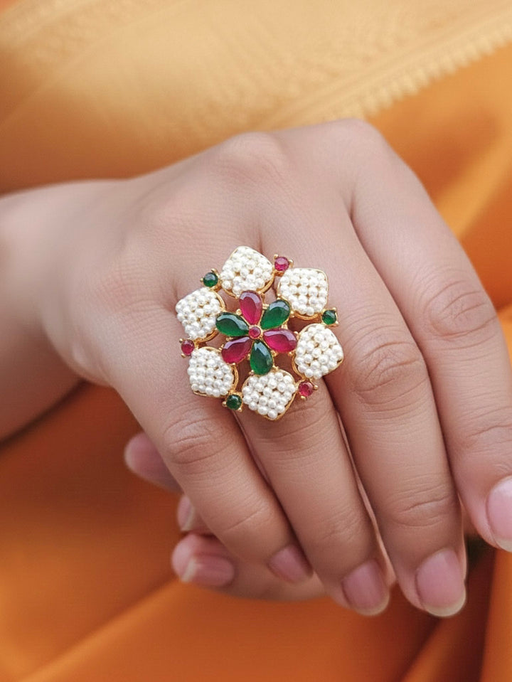 Close-up of a woman wearing an ornate traditional (Bright Gold Polish) Red,Green and White Collar jewellery set and earrings and Ring with Pearls and Red & Green Colored Stones. Mehendi ceremony look completed with a handcrafted Pearl jewelry set. Woman wearing a vibrant Pearl artificial jewelry set for celebrations.