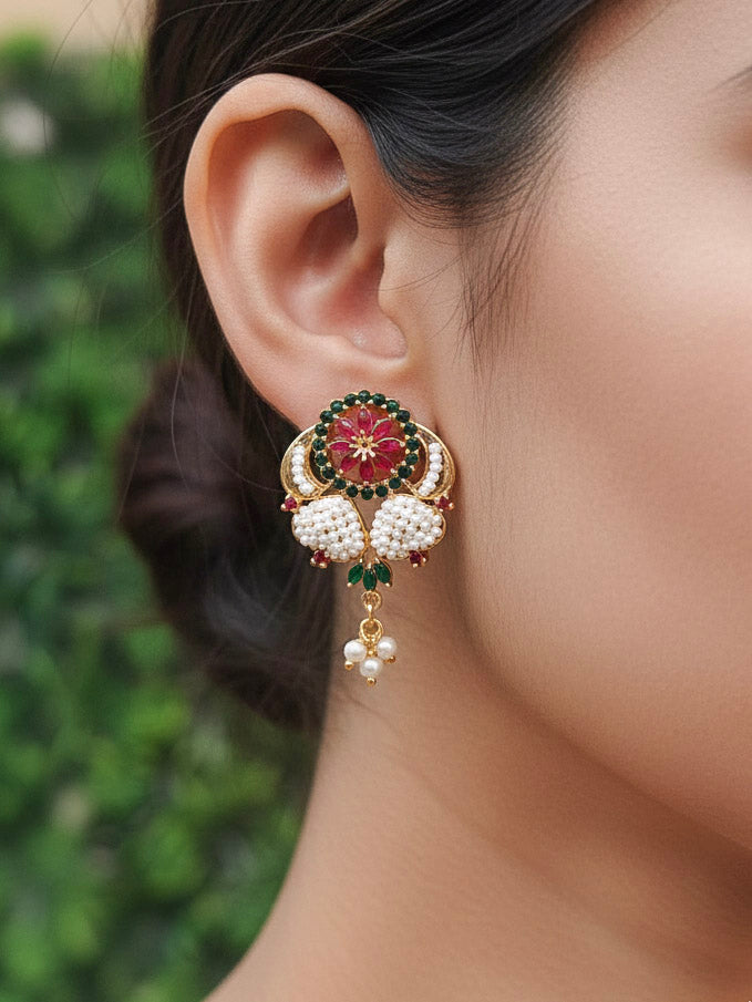 Close-up of a woman wearing an ornate traditional (Bright Gold Polish) Red,Green and White Collar jewellery set and earrings and Ring with Pearls and Red & Green Colored Stones. Mehendi ceremony look completed with a handcrafted Pearl jewelry set. Woman wearing a vibrant Pearl artificial jewelry set for celebrations.